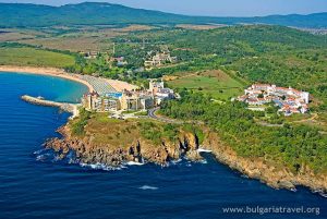 Aerial view of coastal resort with palm trees, pool, and beachfront villas