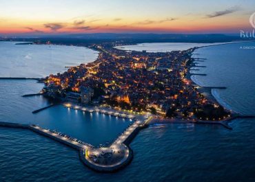 an aerial view of a city with lights on a body of water