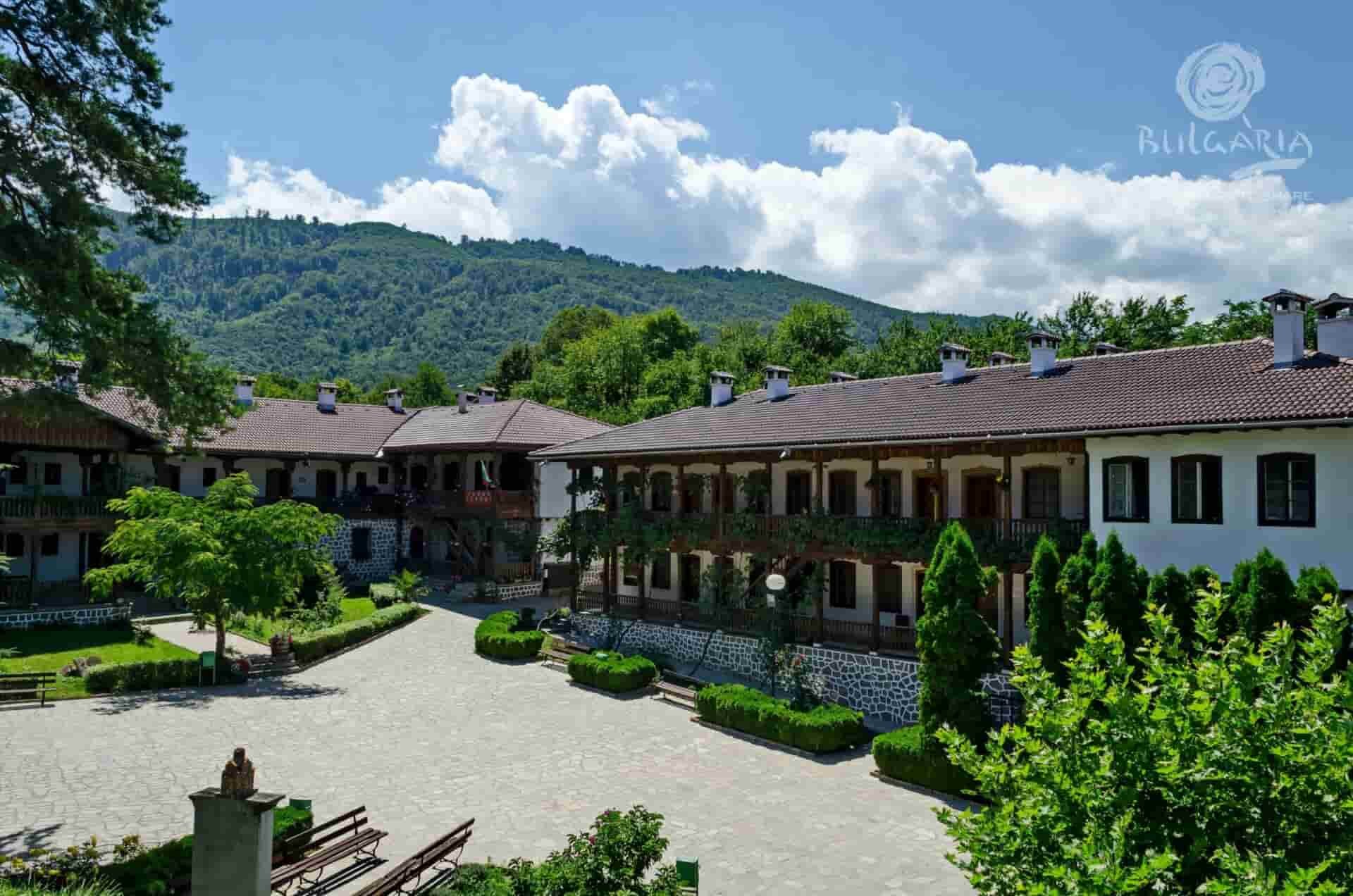 A spacious courtyard with trees and mountains in the background, enhancing the grandeur of the large building.